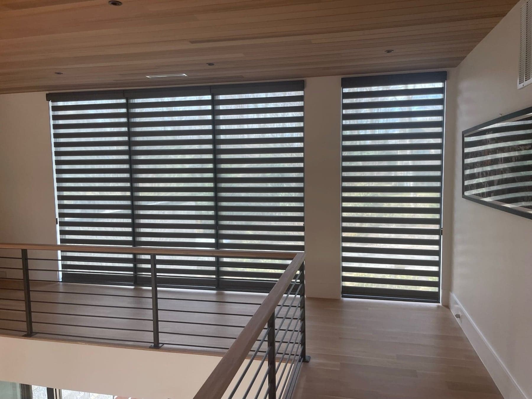 Floor-to-ceiling banded shades on tall loft windows under a wood-plank ceiling